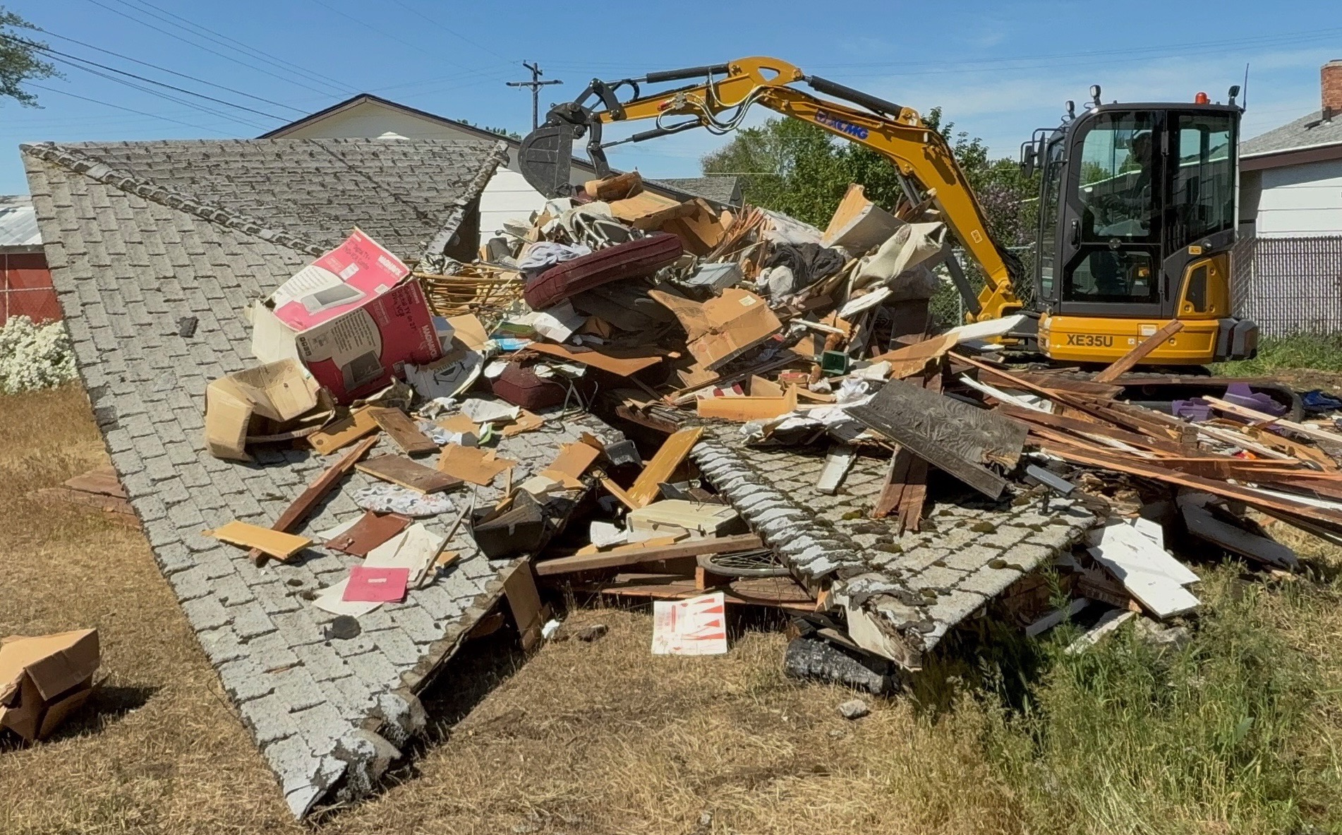 Trash Bandits excavator beside dismantled roofing and timber during garage site preparation