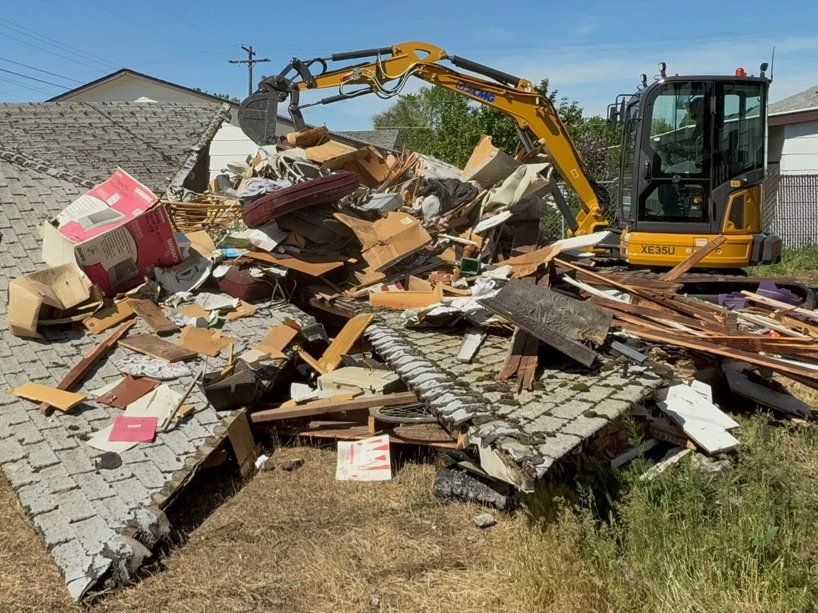 Excavator alongside roofing and timber during demolition for a new garage